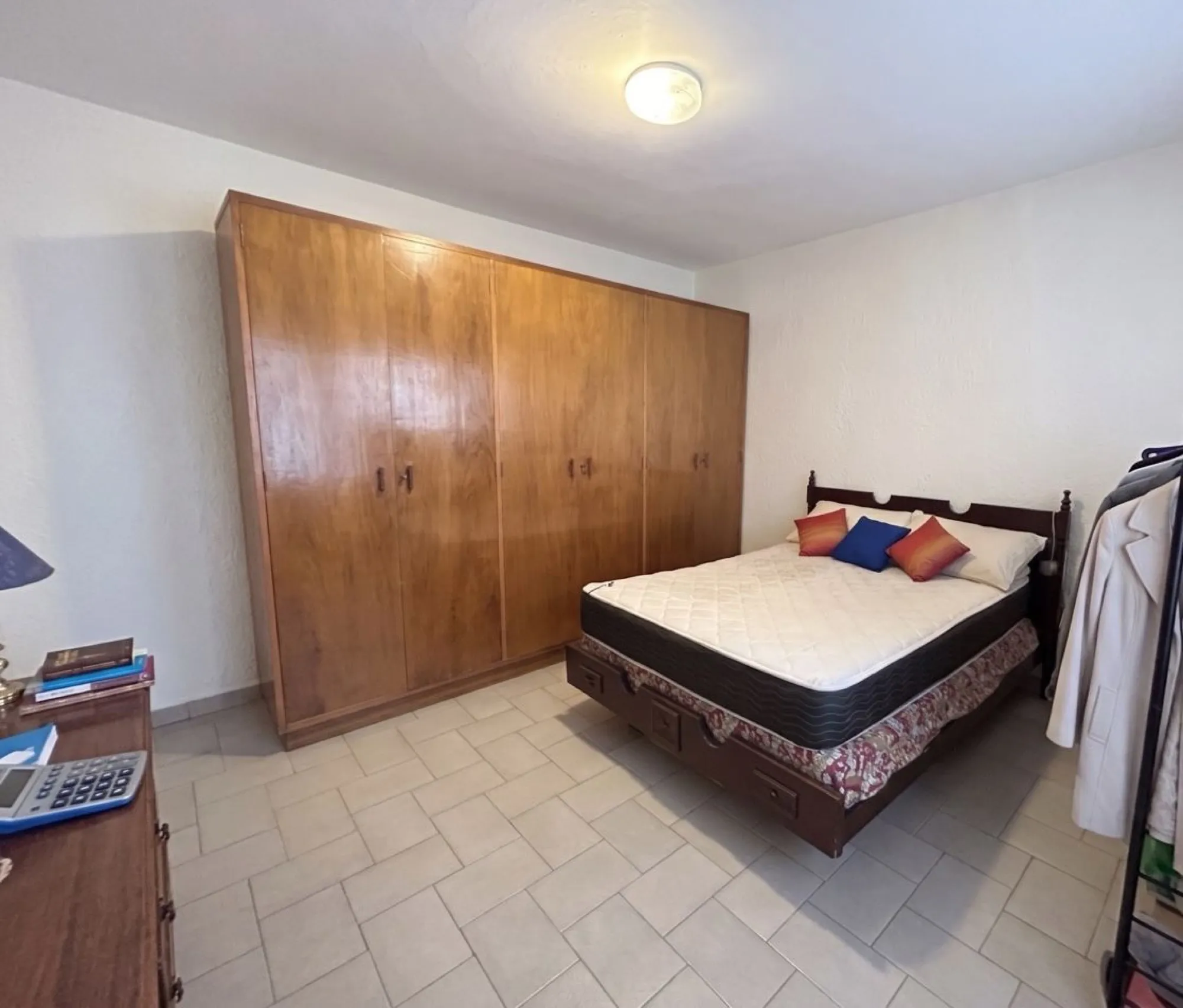 Dormitorio con cama matrimonial y un placard de madera.